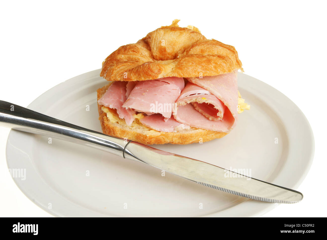 Schinken gefüllt Croissant auf einem Teller mit einem Messer Stockfoto