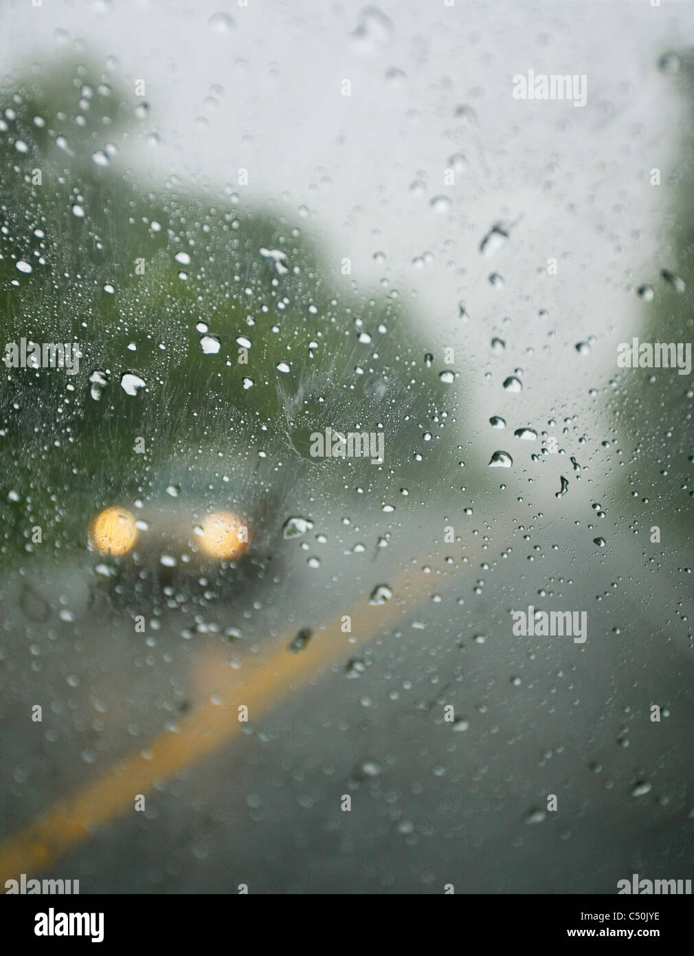 ein Auto fahren im Regen mit Scheinwerfer auf, wie von innen ein anderes Auto zu sehen. Stockfoto