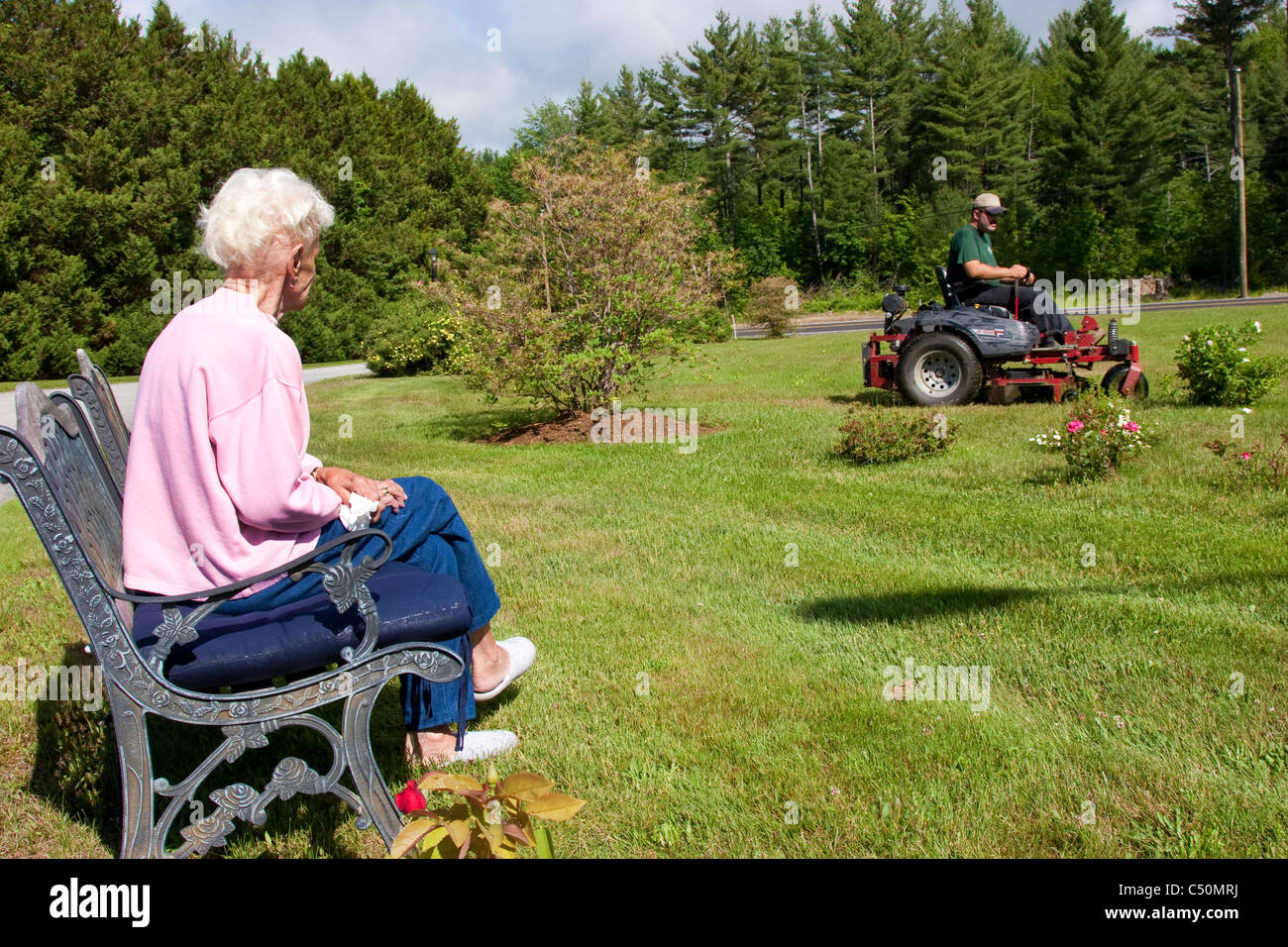 Rasen-Pflege-Service ältere Frau Rasen zu mähen, während sie Uhren Stockfoto