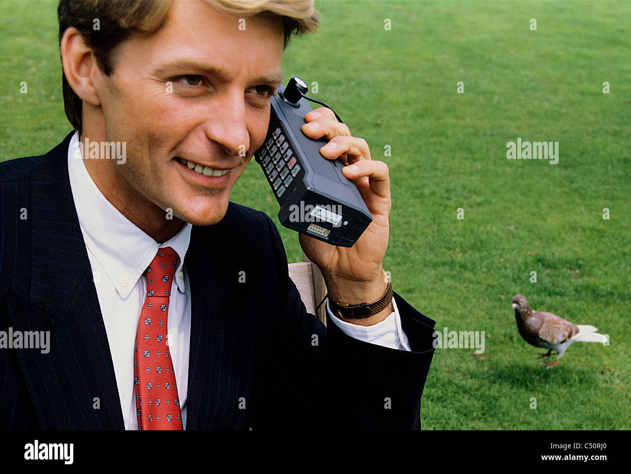 Achtziger Jahre Geschäftsmann auf "Ziegelstein" Stil Vintage Handy, in einem Park. Stockfoto