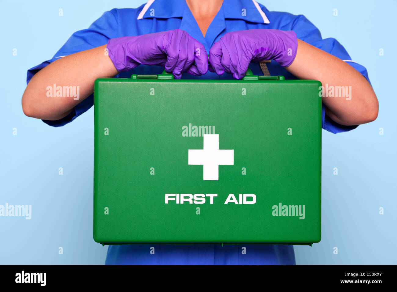 Foto von einer Krankenschwester in Uniform hält einen grünen Verbandskasten. Stockfoto