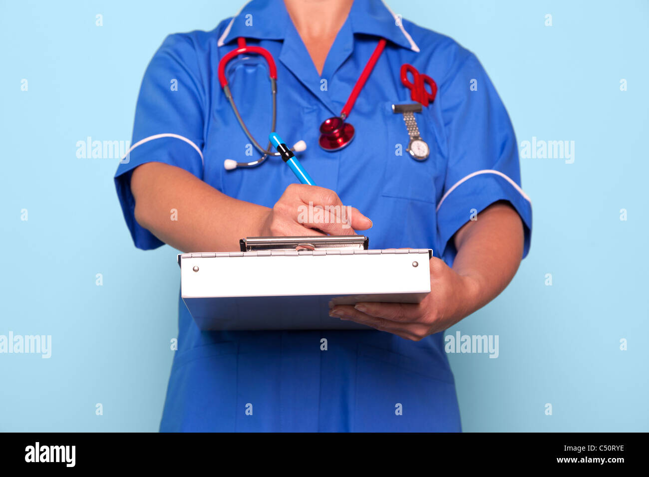 Foto von einer Krankenschwester in Uniform, die einen medizinischen Berichtsordner aktualisieren einige Patienten Hinweise halten. Stockfoto