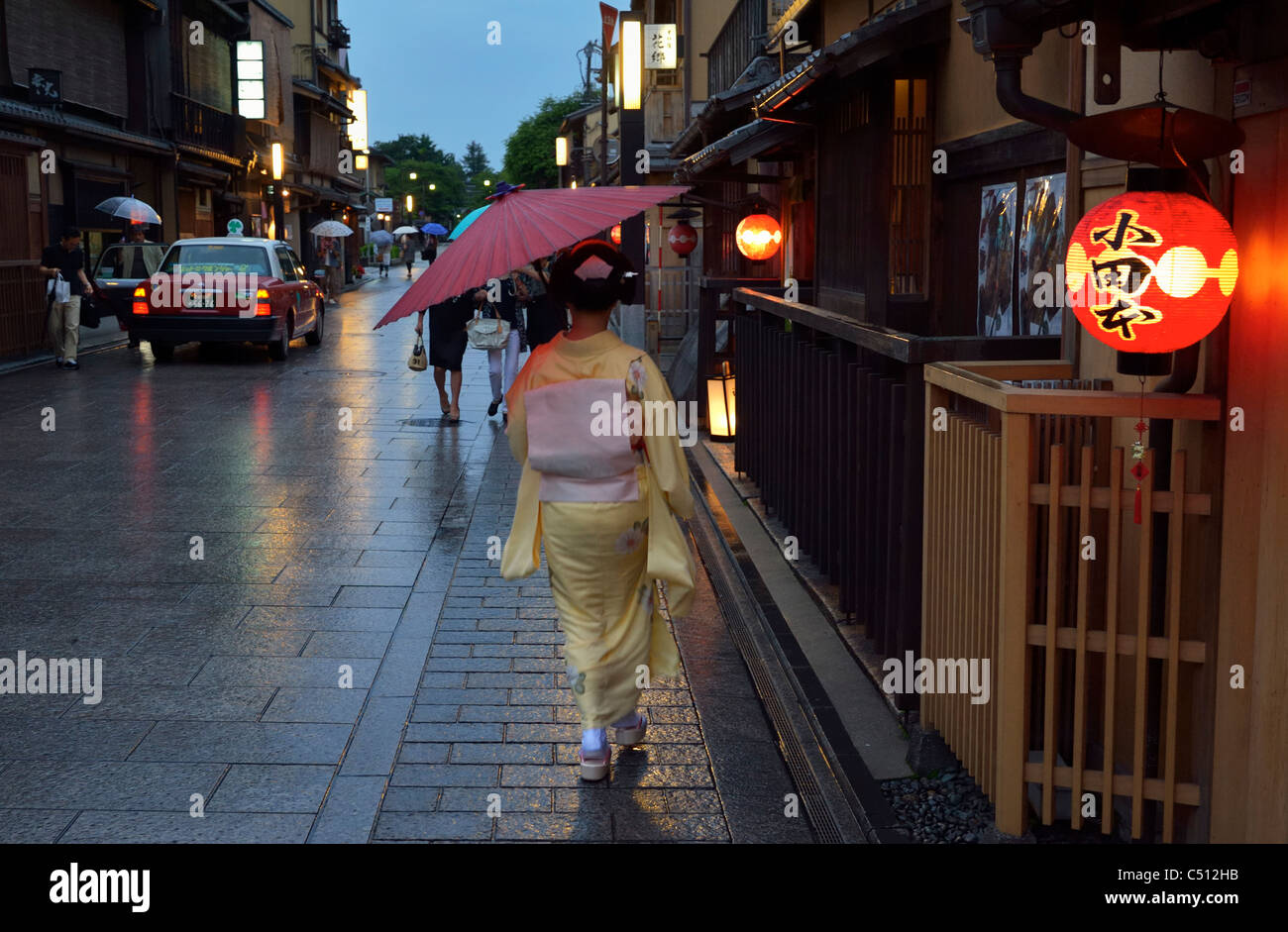 Eine japanische Geisha (Geiko) zu Fuß entlang traditionellen Restaurants im historischen Gion-Viertel, Kyoto, Japan JP Stockfoto