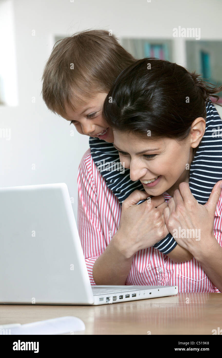 Mutter und junge Sohn am Tisch vor Laptopcomputer Stockfoto