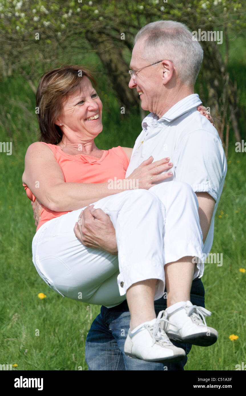 Paar mittleren Alters, Mann, eine Frau in seinen Armen trägt Stockfoto