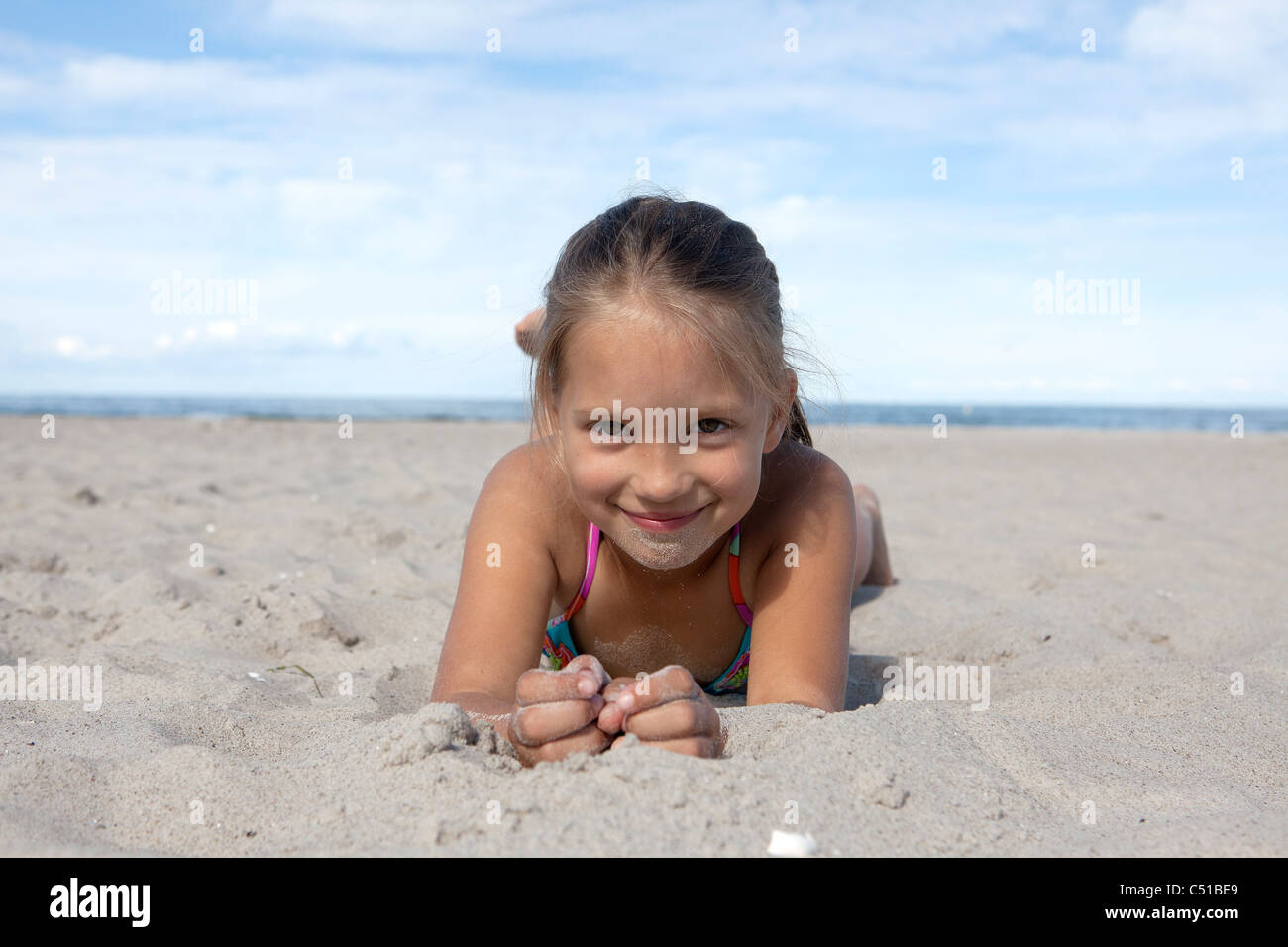 Porträt des jungen Mädchens im Sand am Strand liegen Stockfoto