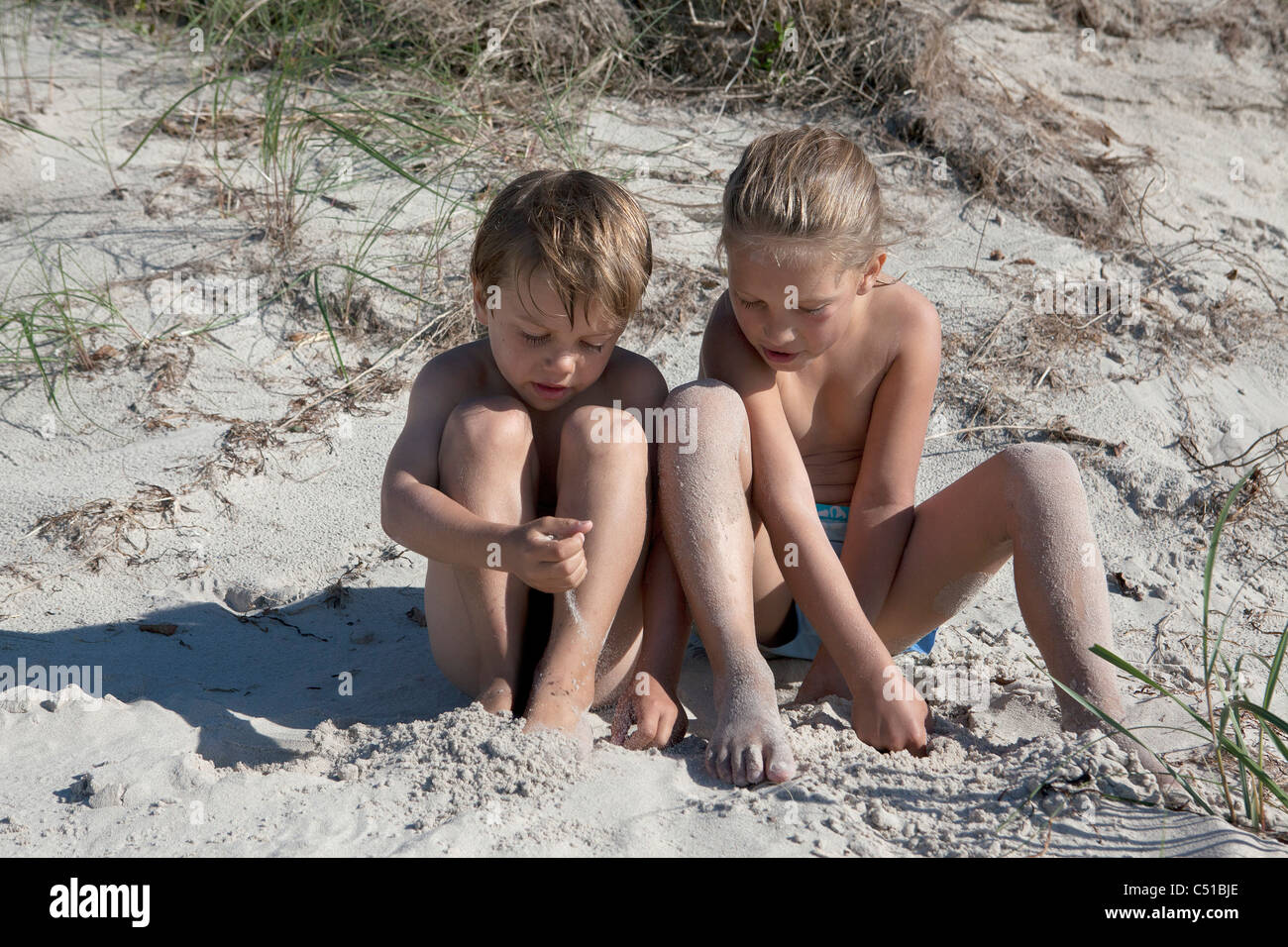 Schwester und Bruder sitzt zusammen im sand Stockfoto