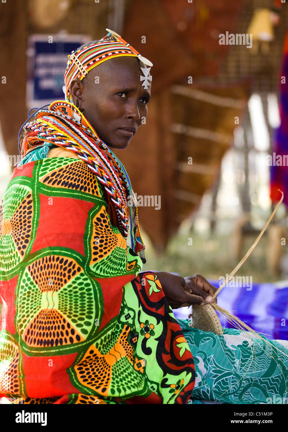 Eine kenianische Frau in traditioneller Kleidung weben einen Korb Stockfoto