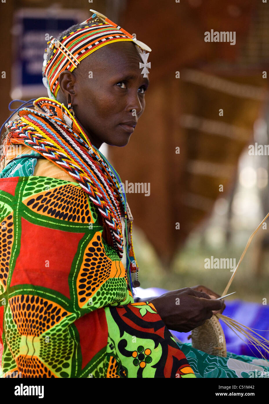 Eine kenianische Frau in traditioneller Kleidung weben einen Korb Stockfoto