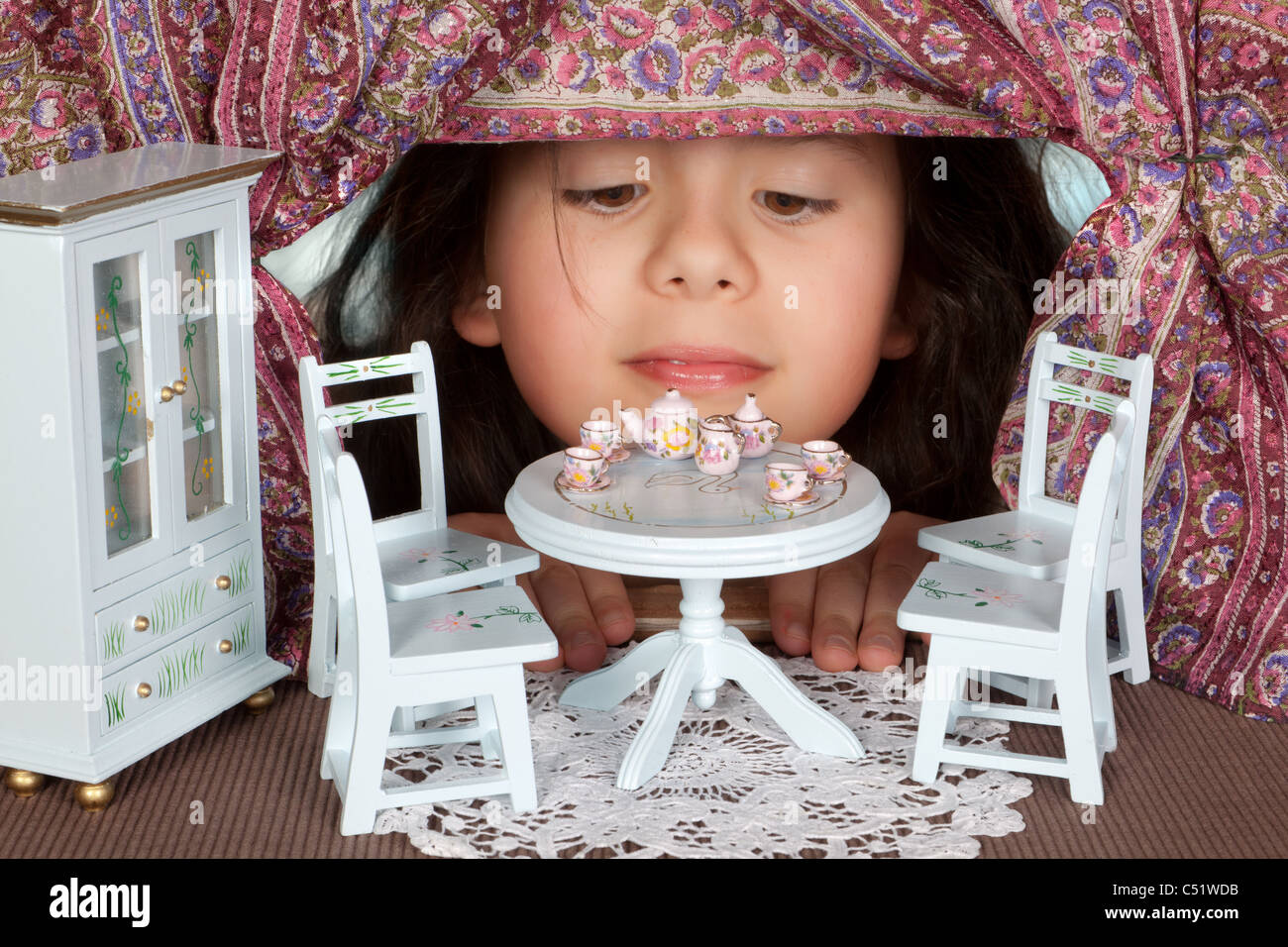 Mädchen auf der Suche in ein Miniaturhaus wie Alice im Wunderland Stockfoto