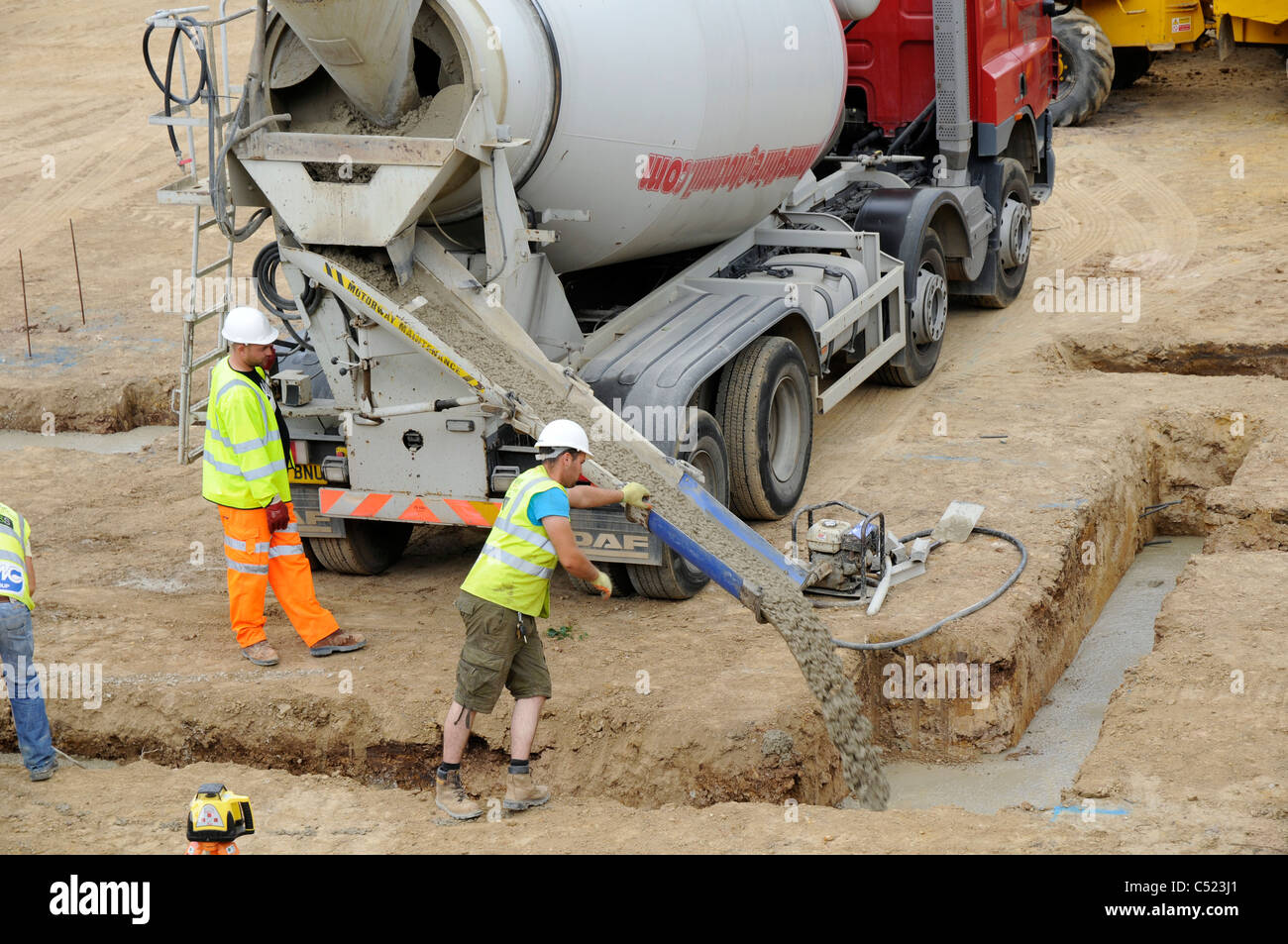 Baustelle zeigt Streifen Stiftung Gräben und Betonmischer liefern konkrete. Stockfoto