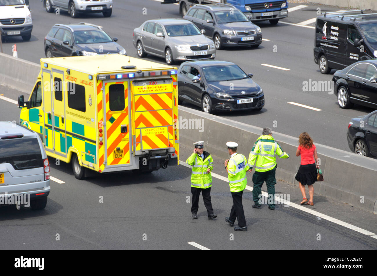Sanitäter Escort Frau, die wartenden Krankenwagen in Szene der Autobahn Auto crash (unter Brücke), während Polizeikontrolle Unfallhergang Stockfoto