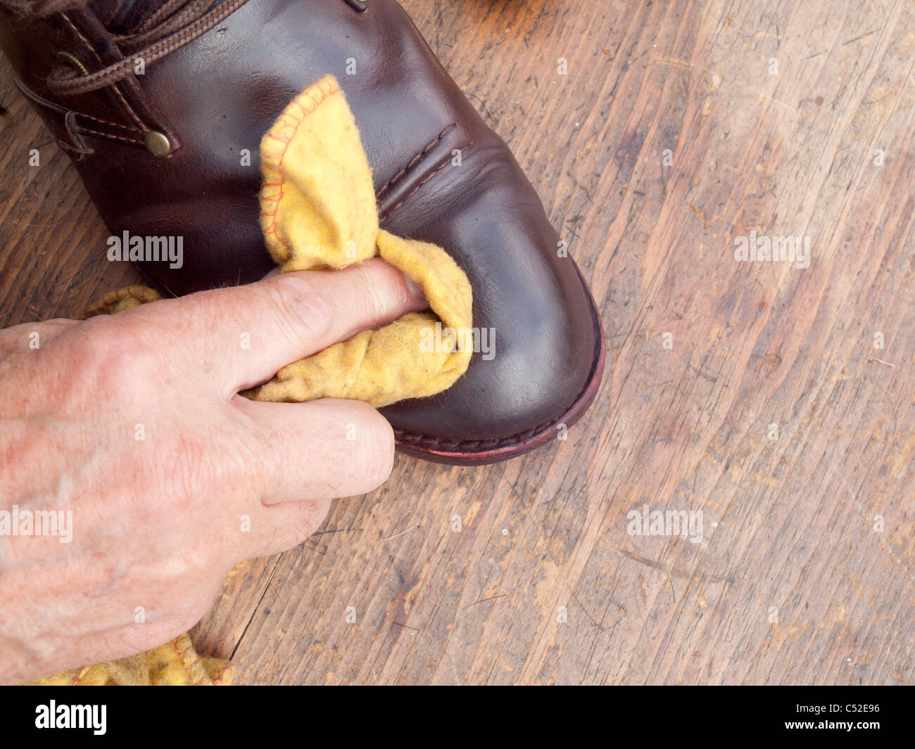 Einen braunen Stiefel mit einem gelben Staubtuch Polieren Stockfoto