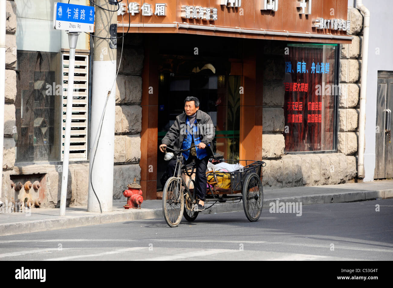 Ein Mann reitet seine Dreirad in Shanghai Stockfoto