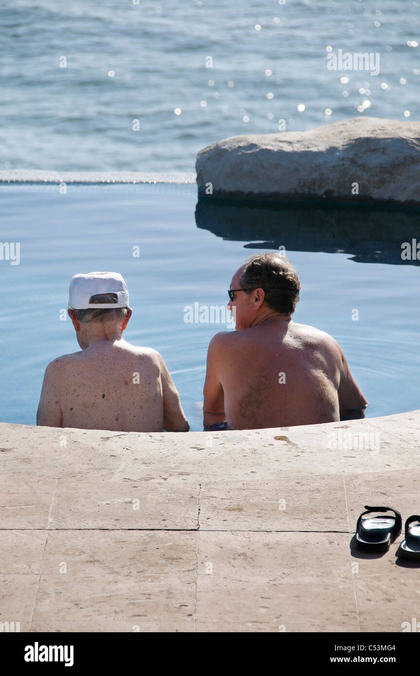 Ein senior männlichen Erwachsenen und älteren Vater entspannen Sie sich in einem Schwimmbad mit Blick auf den Pazifischen Ozean in San Pancho, Mexiko. Stockfoto