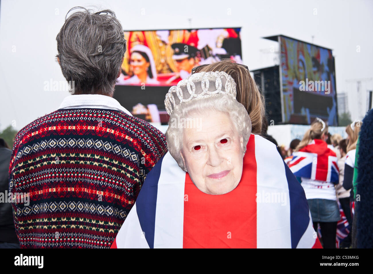 Menschen feiern er königliche Hochzeit im Hyde Park mit Union Jack-Flagge und die Königin-Maske. Stockfoto