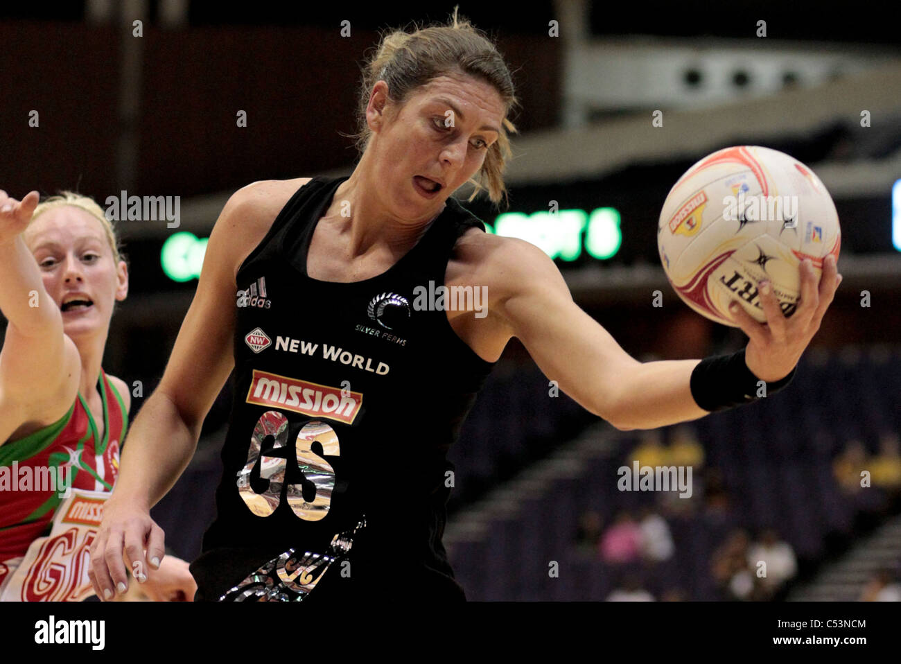 05.07.2011 verbindet Irene van Dyk Neuseelands mit dem Pass, während Stephanie Williams im Pool B Spiel zwischen Neuseeland und Wales, Mission Foods Netball Weltmeisterschaften 2011 vom Singapore Indoor Stadium in Singapur zusieht. Stockfoto