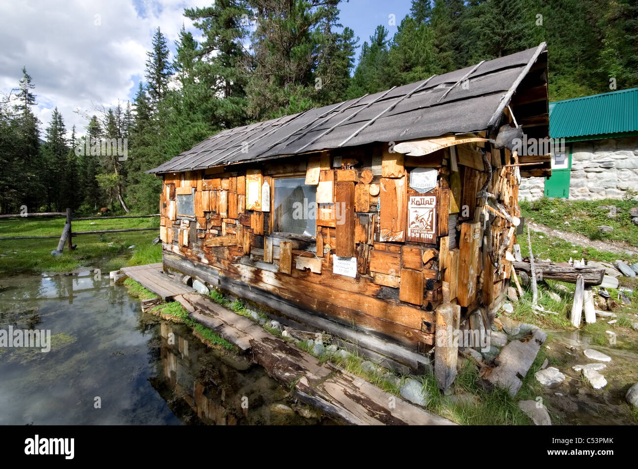 Hütte in der Taiga mit nationalen Symbolen, Bildern und Mineralbad in Holz. Mineralquellen Sajan-Gebirge. Sibirien. Russland. Stockfoto