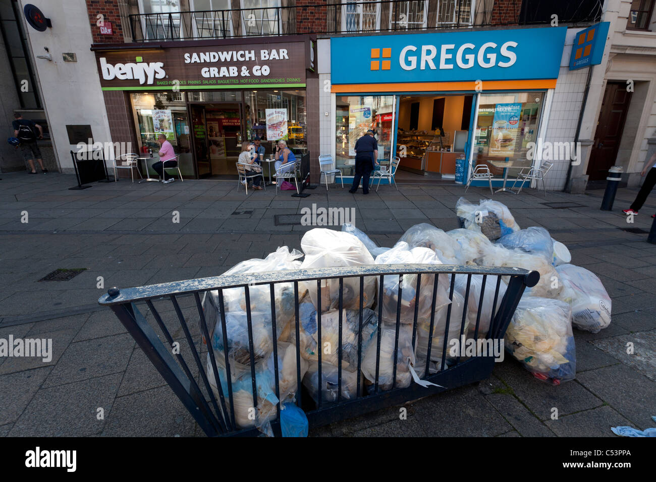 Müll-Taschen-Pfähle außen Fast-Food-Läden - Greggs und Benjys Stockfoto