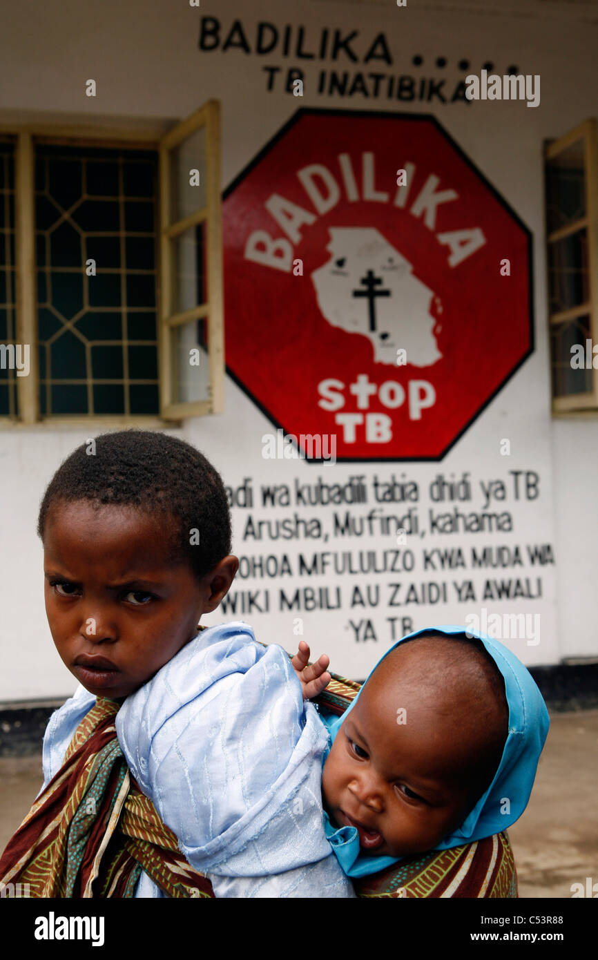 Ein Kind trägt ein weiteres Kind zu einer Einheit der Ngarennaro Community Health Centre, Arusha, Tansania. Stockfoto