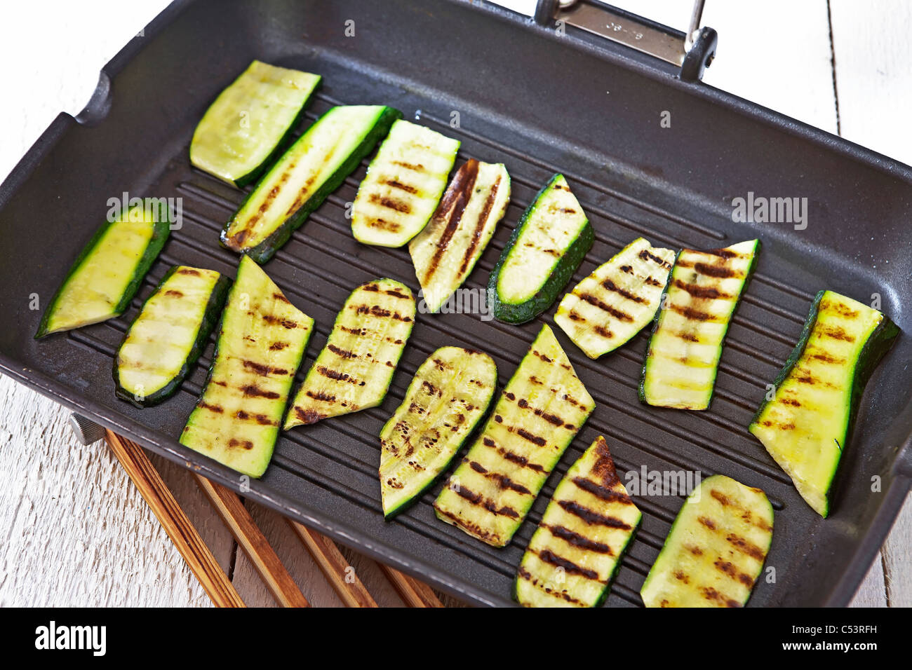 Gegrillte Zucchini mit Olivenöl in einer Pfanne erhitzen Stockfoto
