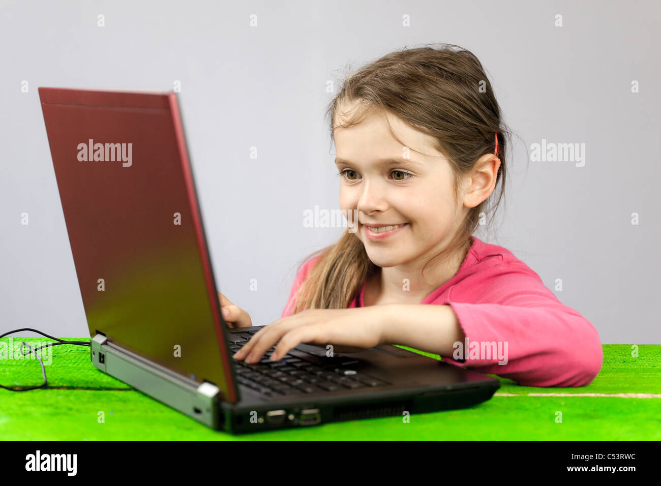 ein sieben Jahre altes Mädchen auf einem Laptop, Hausaufgaben zu machen Stockfoto