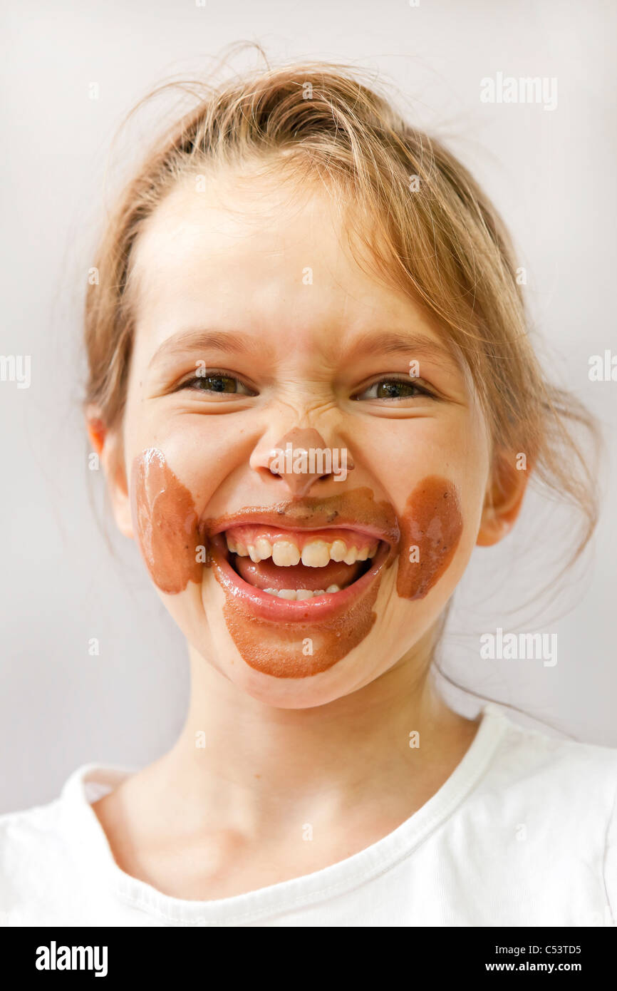 ein sieben-jährige mit Schokoladeneis in das Gesicht, das sich freut Stockfoto