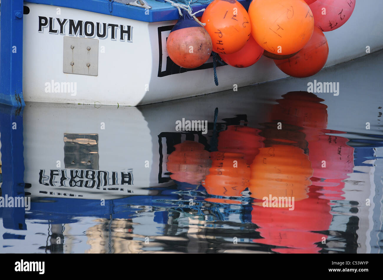 Reflexionen von einem Fischerboot und Bojen, Sutton Harbour, Plymouth, Großbritannien. Stockfoto