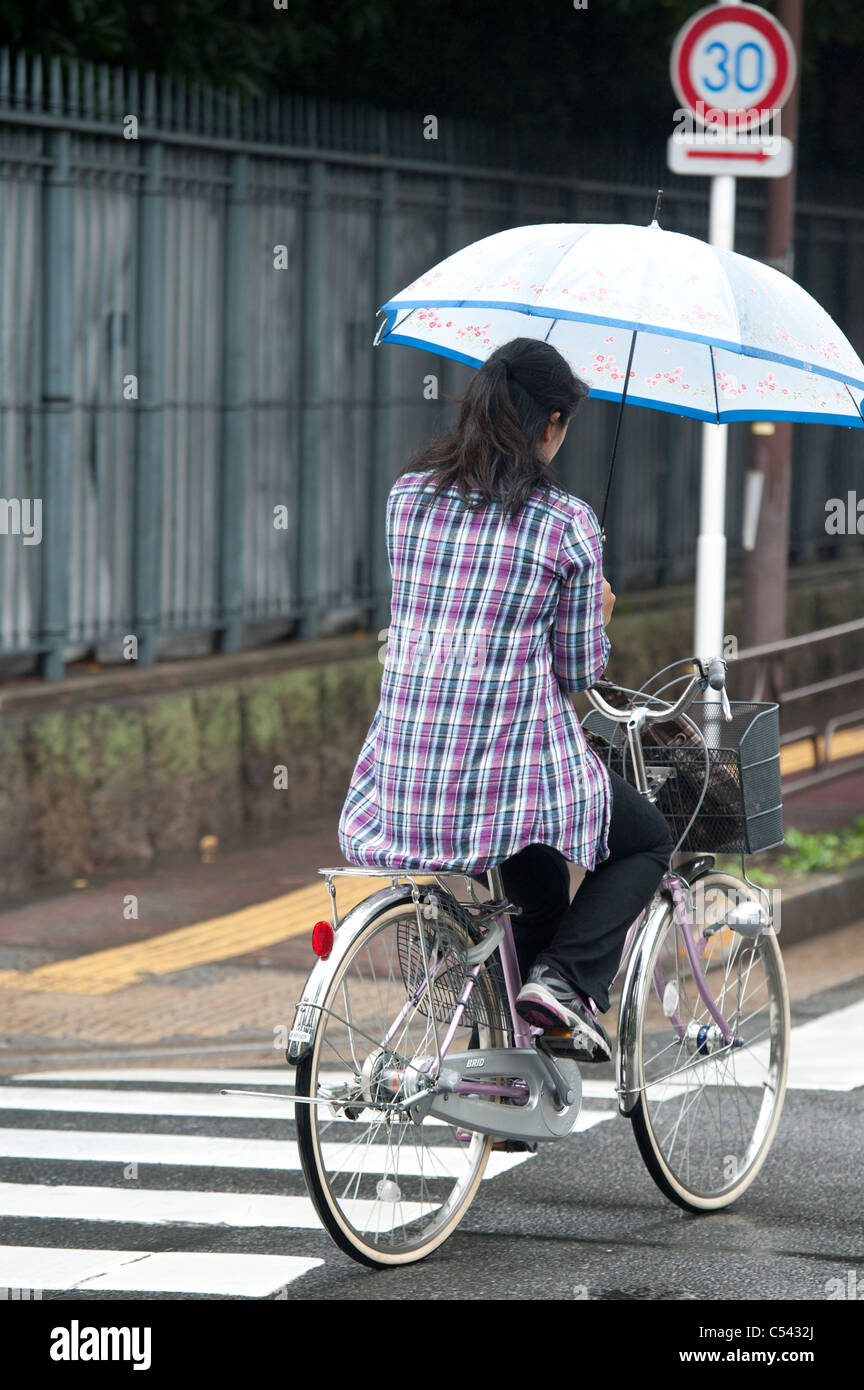 Frau mit dem Fahrrad mit der holding eines Regenschirm, Tokyo, Japan  Stockfotografie - Alamy
