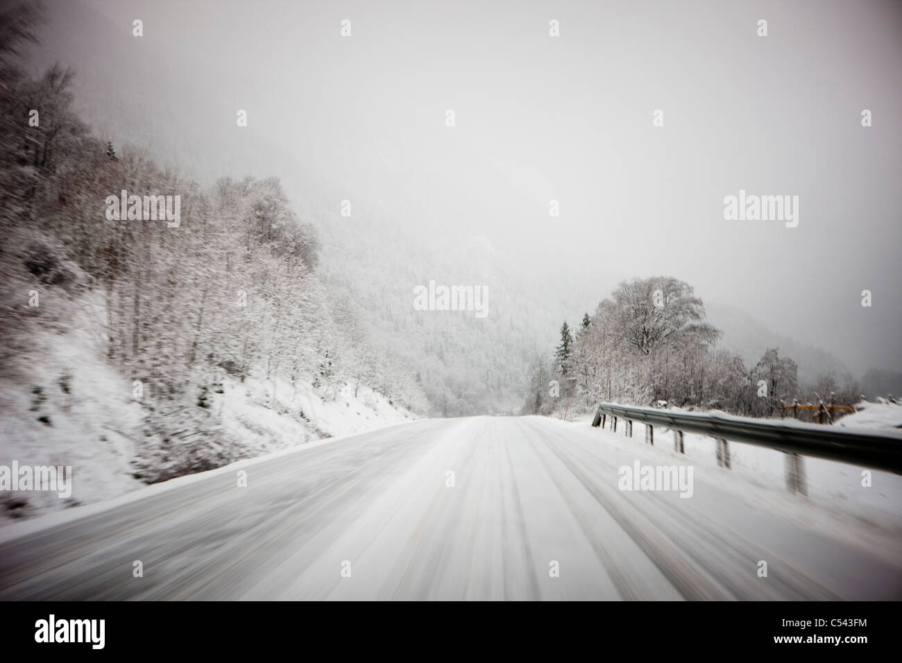 Winter Wald Bergstraße mit felsigen Seiten ist verschwommen und in der Ferne die verschneite Wetter macht es unklar zu sehen Stockfoto