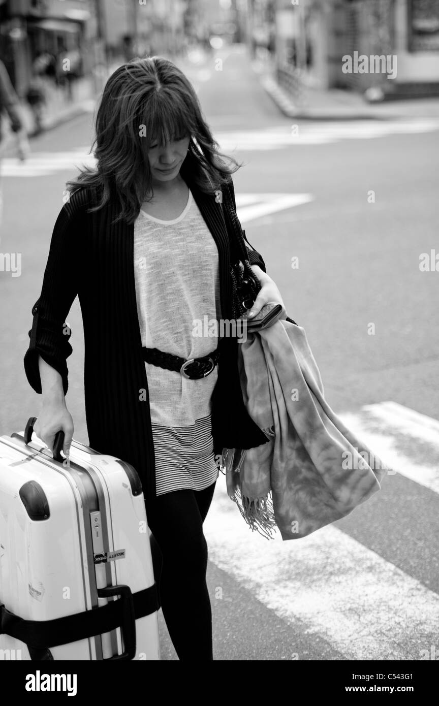 Frau beim Überqueren der Straße mit Gepäck, Tokyo, Japan Stockfoto