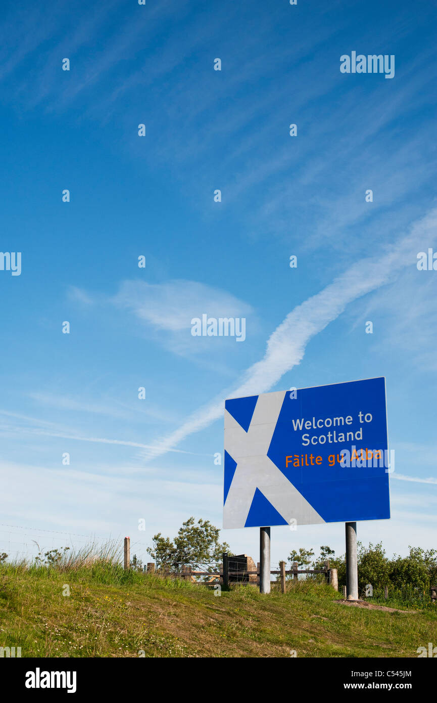 Schottland-Grenze-Zeichen an der Northumberland-Grenze vor einem weißen Kreuz Flugzeug Trail in den blauen Himmel Stockfoto