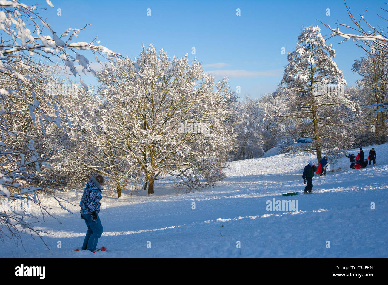 Verschneite Landschaft mit Kinder mit Schlitten, Burghfield Common, Reading, Berkshire, England, UK Stockfoto