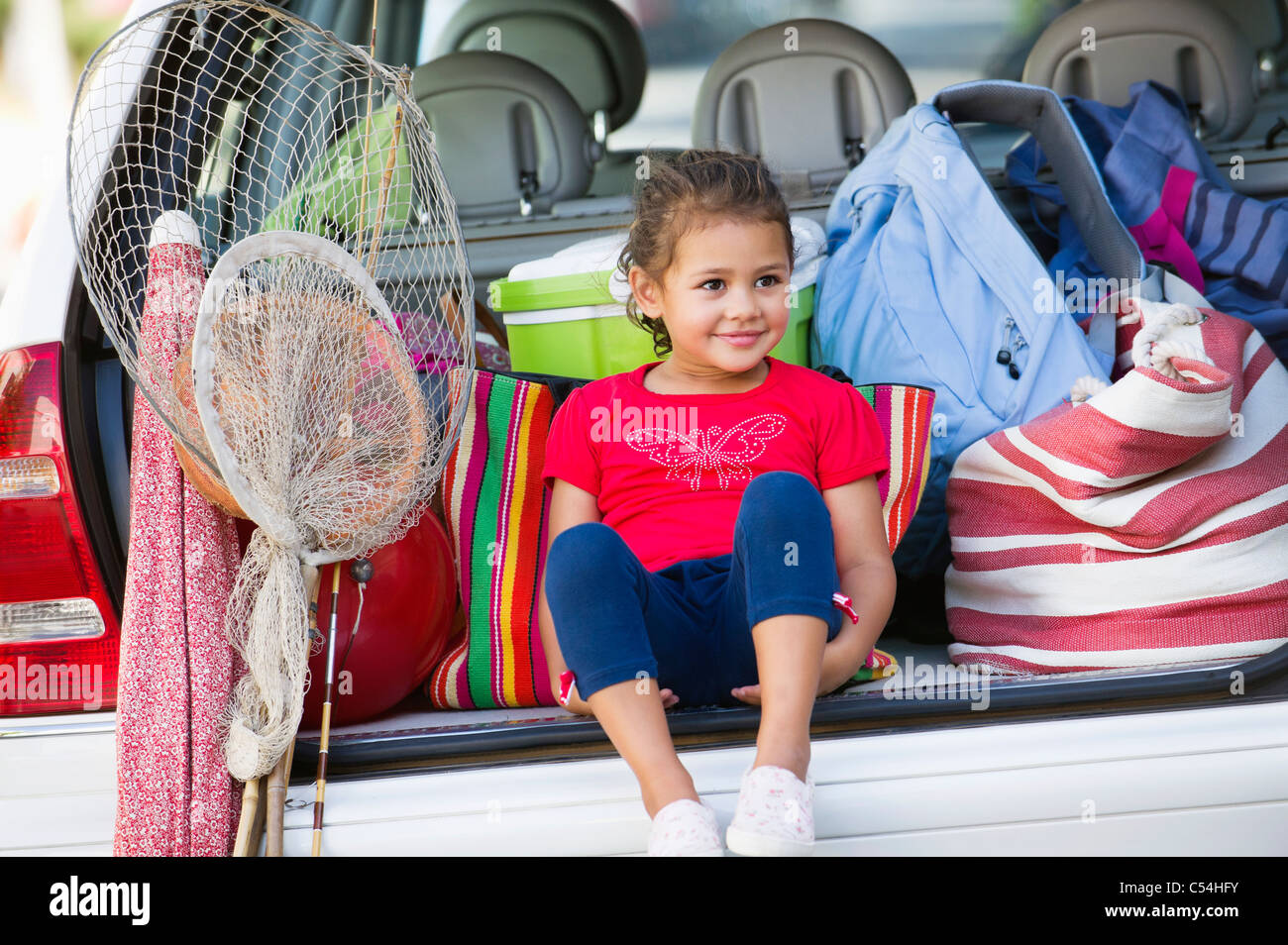Niedliche kleine Mädchen sitzen im Kofferraum eines Autos Stockfoto