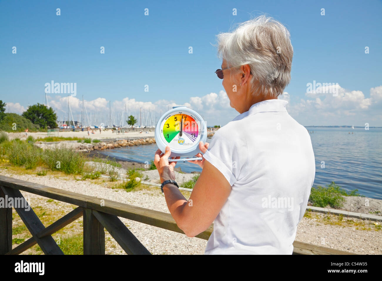 Frau, die einen hohen UV-Index in der Nachmittagssonne auf eine tragbare Sonne UV-Station am Strand zu messen. Stockfoto