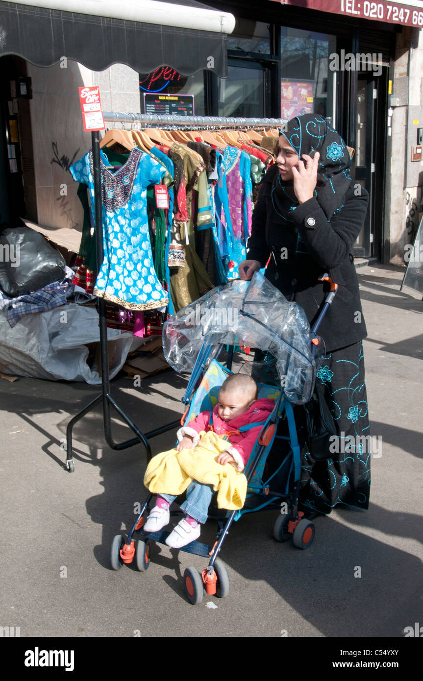 VEREINIGTES KÖNIGREICH. Muslimische Frau mit Handy und Baby im Kinderwagen  Einkaufen in Whitechapel Markt in London Stockfotografie - Alamy