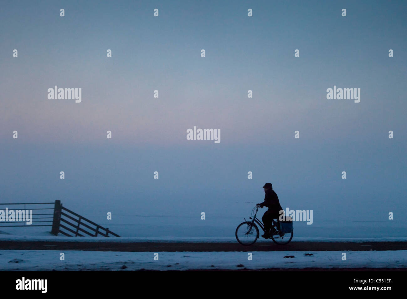 Der Niederlande, in der Nähe von Sneek, Radfahrer in der Morgendämmerung im Winter. Minus 12 Grad Celsius. Stockfoto