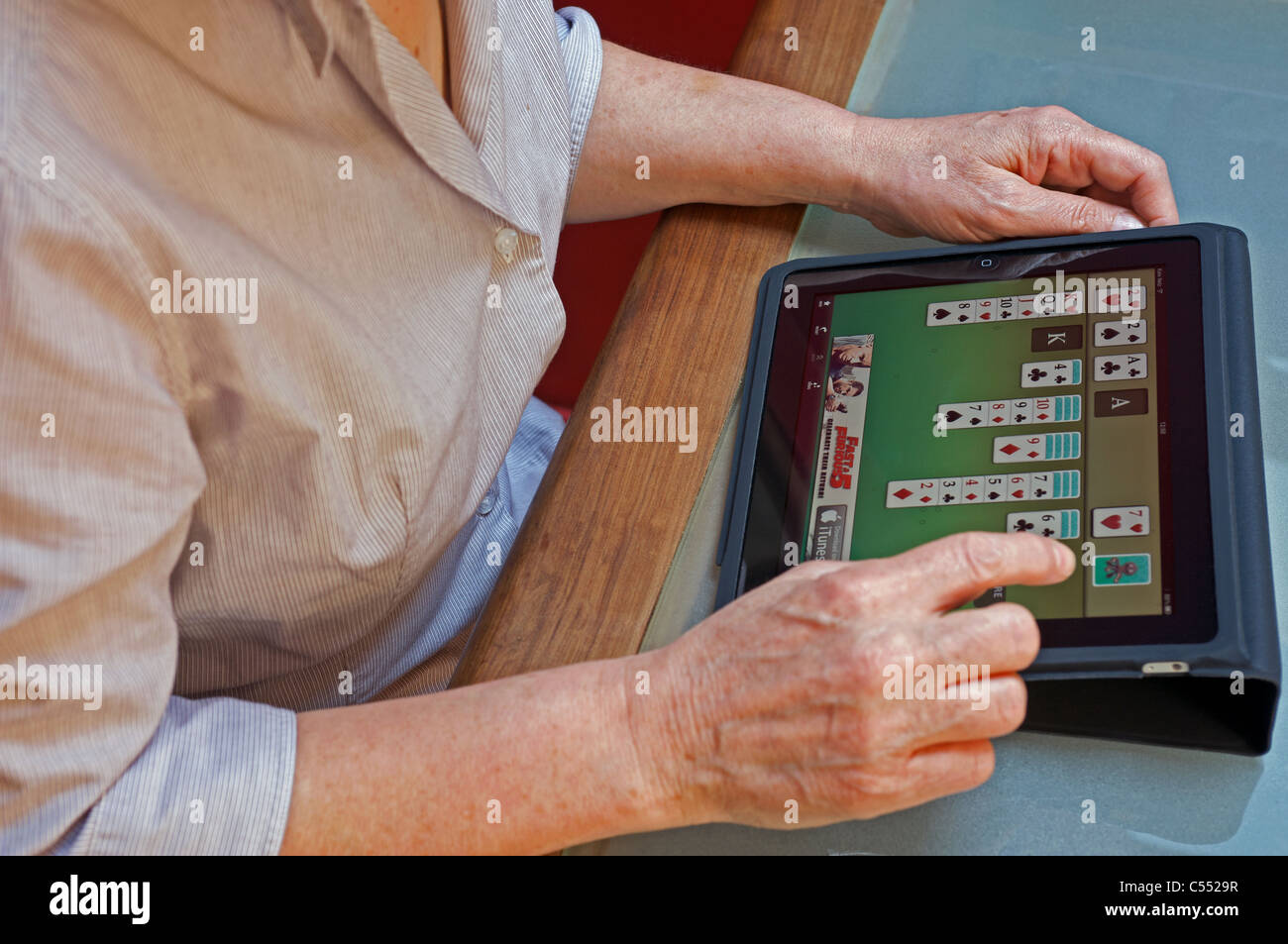 Frau, die ein Spiel Geduld Kartenspiel auf ein Apple iPad Tablet-computer Stockfoto