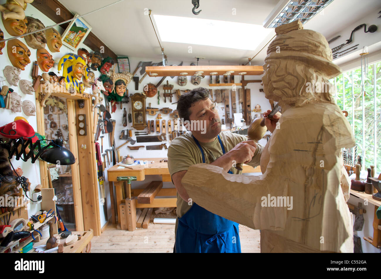 Holzschnitzer arbeiten auf eine große Skulptur in seiner Werkstatt in