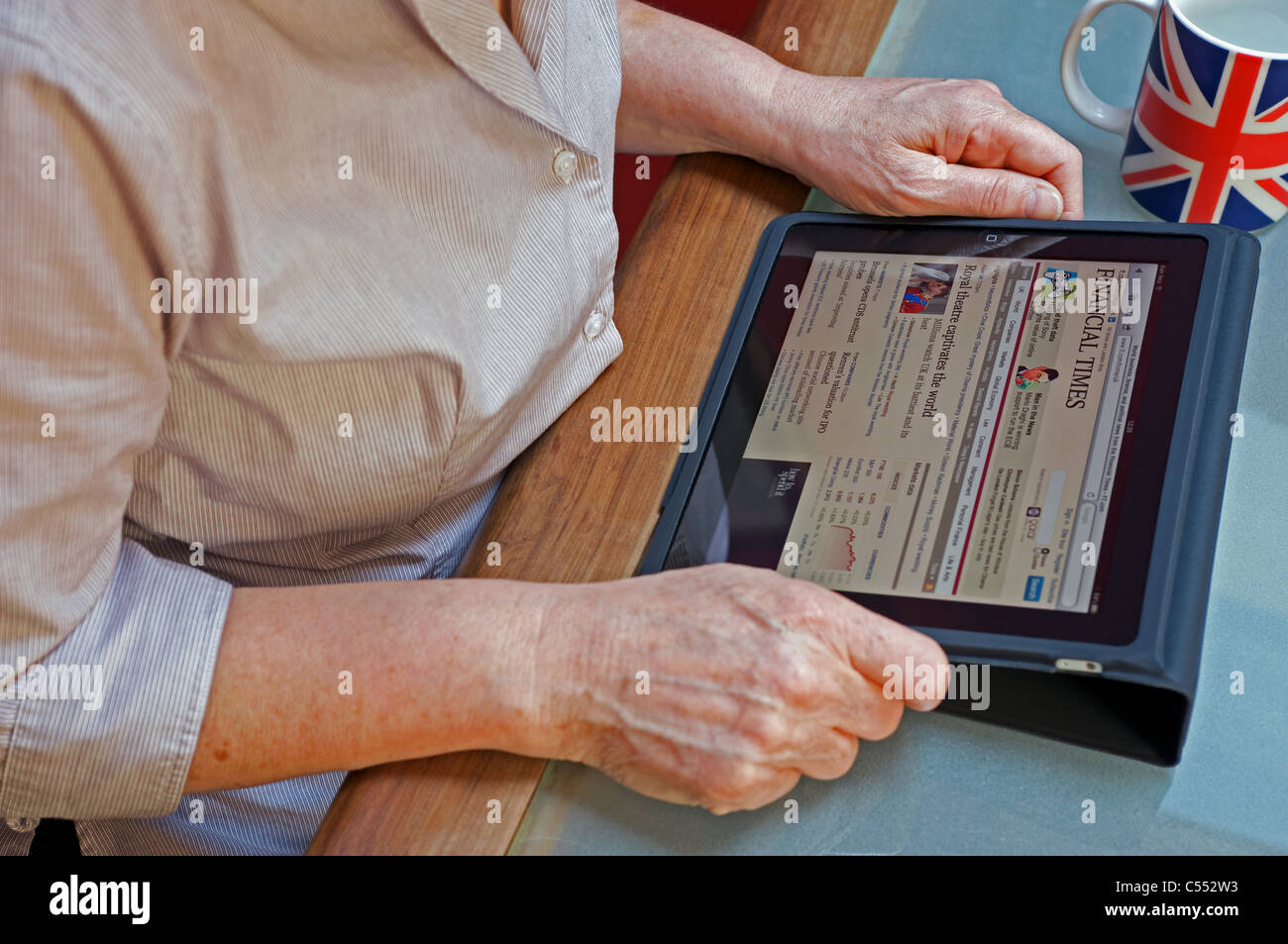 Frau mit Tablet-PC auf der Online-Ausgabe der Financial Times (FT) Stockfoto