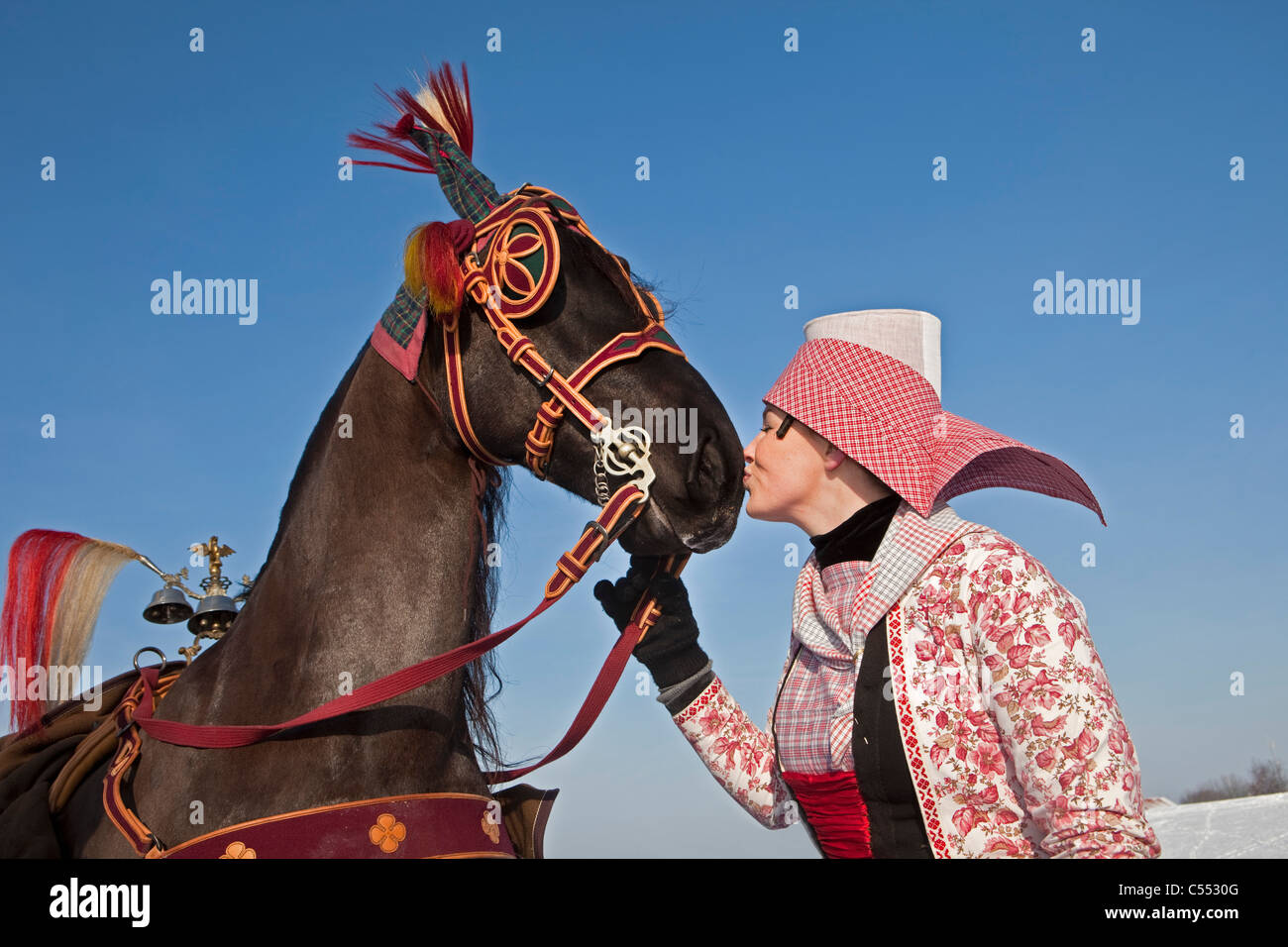Die Niederlande, Hindeloopen, Frau in Tracht geben Kuss auf die Nase des Friesenpferdes. Stockfoto