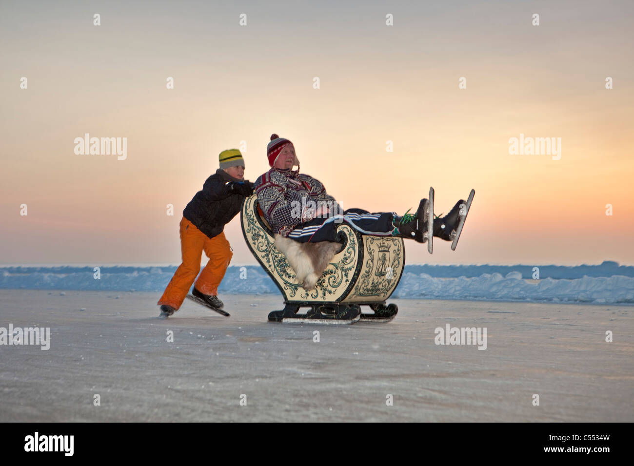 Niederlande, Hindeloopen, der niederländischen Hauptstadt des Eislaufs Kultur. Junge auf Drängen seines Vaters in antiken Schlitten Schlittschuhe. Stockfoto