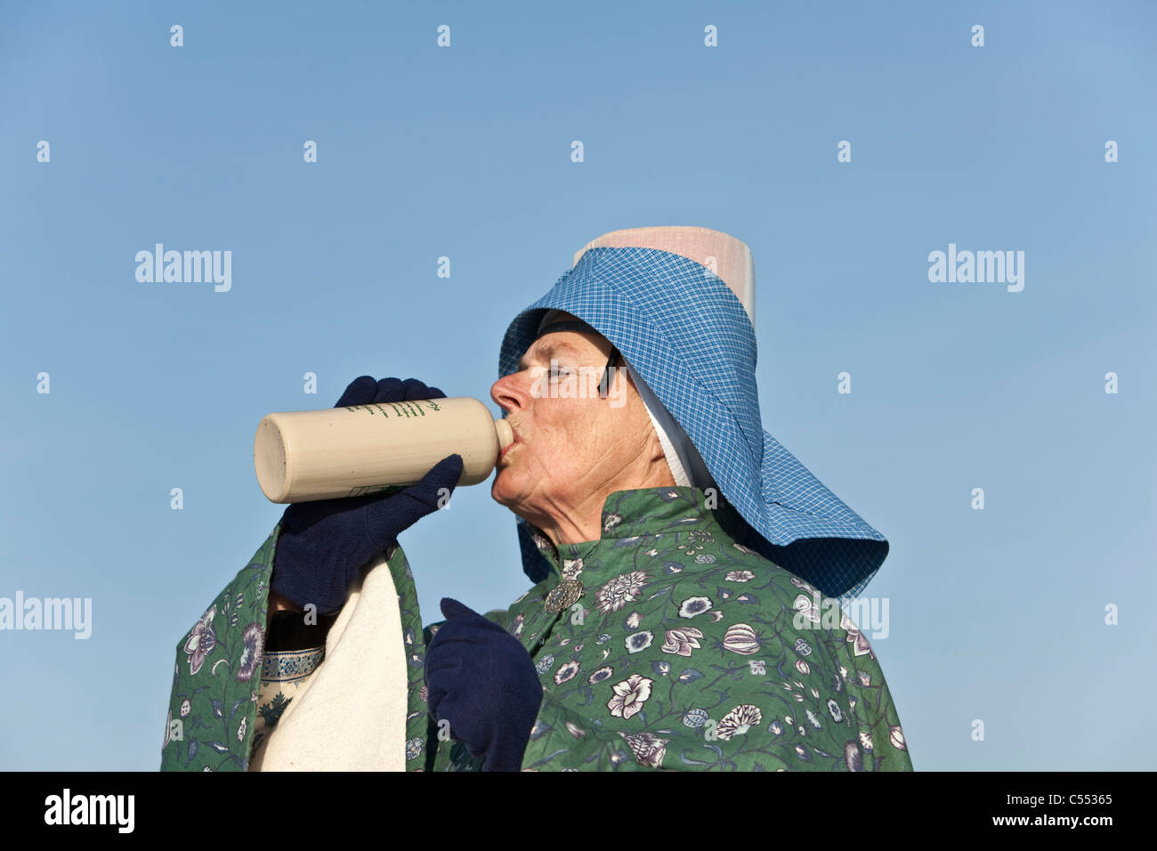 Niederlande, Hindeloopen, niederländische Hauptstadt des Eislaufs Kultur. Porträt der Frau in traditioneller Kleidung, mit einem Drink. Stockfoto