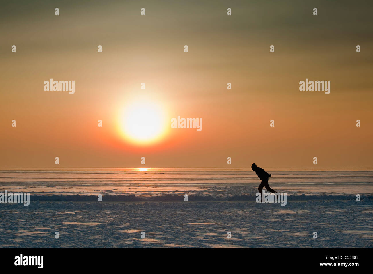 Die Niederlande, Hindeloopen, Eis-Skater auf See namens IJsselmeer bei Sonnenuntergang. Stockfoto