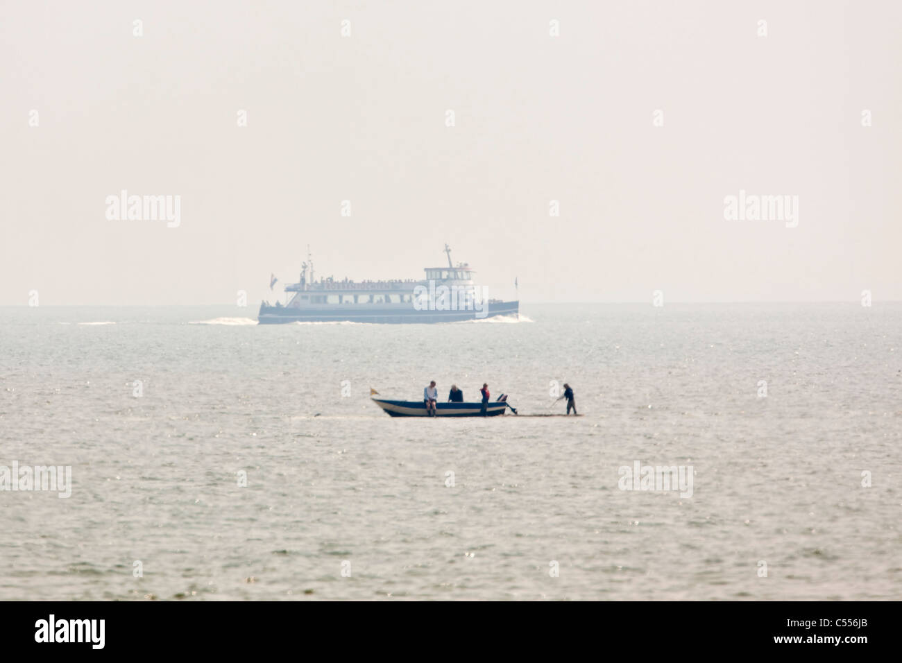 Die Niederlande, Hollum Ameland, Wattenmeer Insel Inseln. Kleines Boot auf Schlamm flach und Tour Boot im Hintergrund. Stockfoto