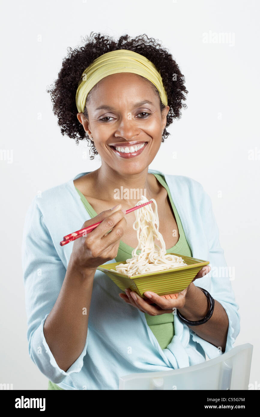 Mitte Erwachsene Frau essen Nudeln mit Stäbchen Stockfoto