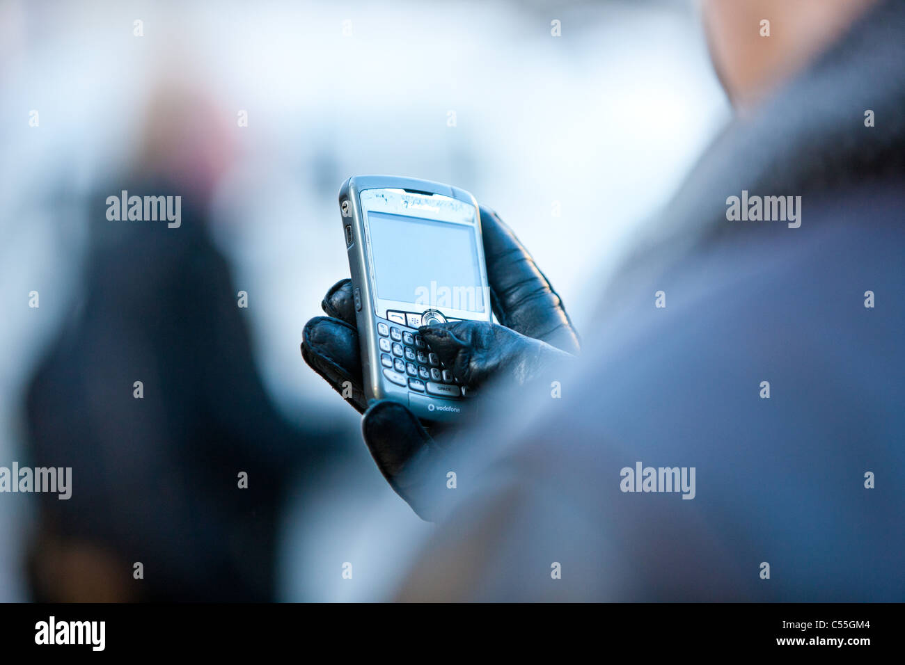 behandschuhten Person SMS auf smart Phone in der Öffentlichkeit Stockfoto