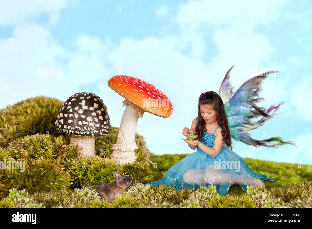 Kleine Fee Mädchen mit Flügeln ein grüner Laubfrosch eine Krone aufsetzen Stockfoto