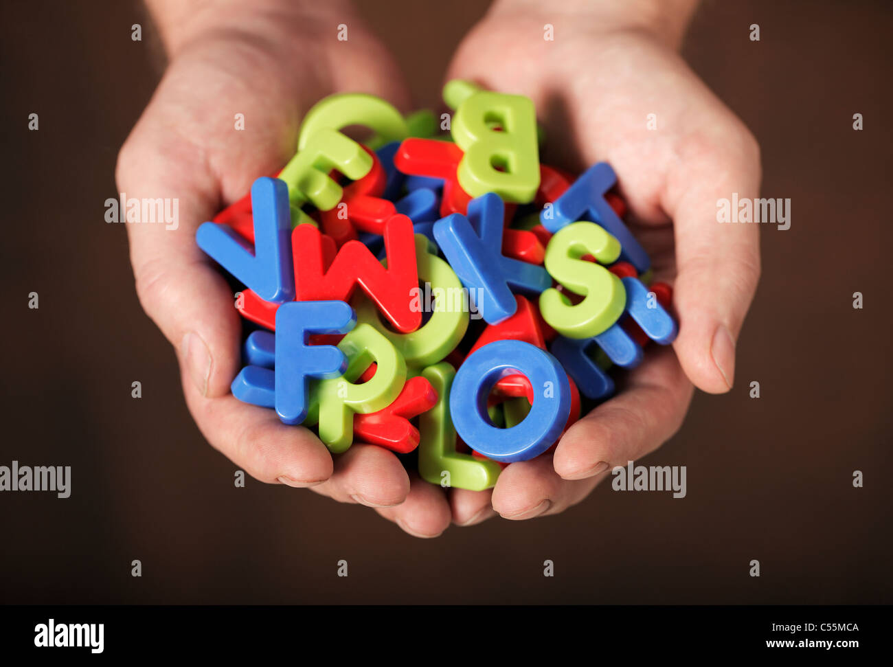 Mann, bunte Kunststoff-Buchstaben in seinen Händen hält. Sehr kurze Tiefenschärfe. Stockfoto