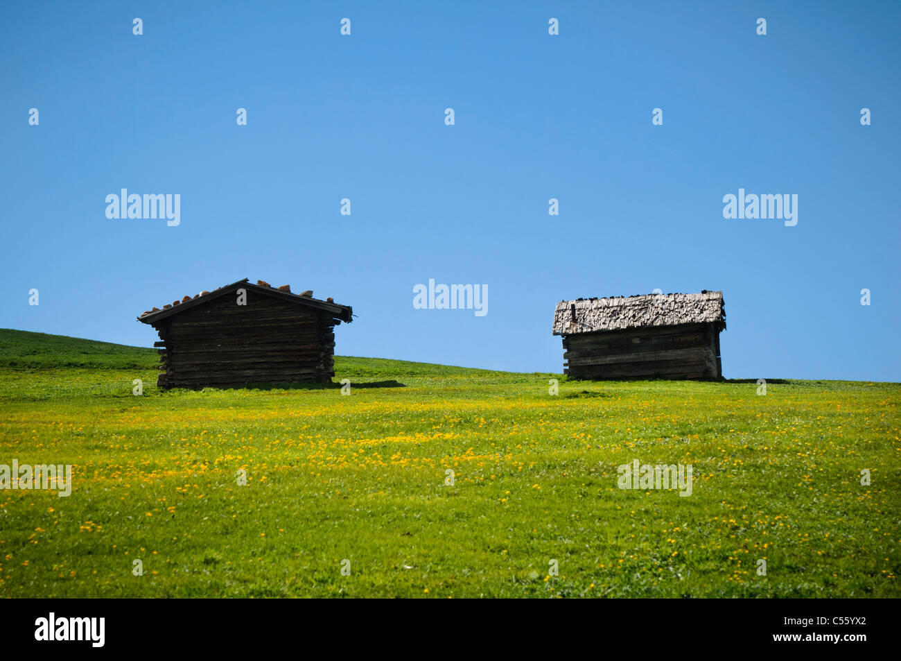 Zwei isolierte alpinen Hütten, Seis Alpen, Italien. Grüne Hügel und blauer Himmel. Stockfoto